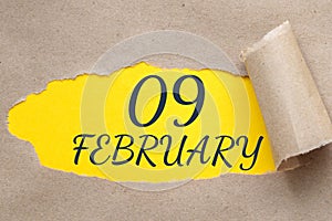 february 09. 09th day of the month, calendar date.Hole in paper with edges torn off. Yellow background is visible