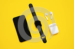 February 09 2021, Rostov, Russia: Smartphone, Apple watch and AirPods with an open case are on yellow background, top