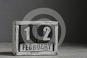 February 12 on wooden calendar, on dark gray background.