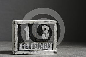 February 13 on wooden calendar, on dark gray background.