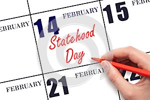 February 14. Hand writing text Statehood Day on calendar date. Save the date.