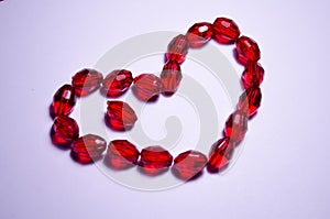 February 14. Heart of beads on a white background in the center. Empty white space. Bright red beads lie in the shape of a heart.