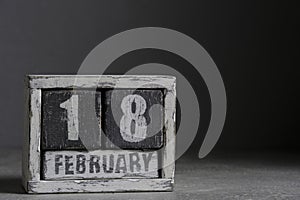 February 18 on wooden calendar, on dark gray background.