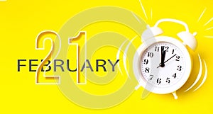 February 21st . Day 21 of month, Calendar date. White alarm clock with calendar day on yellow background. Minimalistic concept of