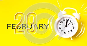 February 29th. Day 29 of month, Calendar date. White alarm clock with calendar day on yellow background. Minimalistic concept of