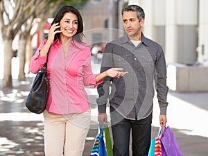 Fed Up Man Carrying Partners Shopping Bags On City Street