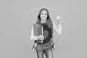 Feed your brain with knowledge. Happy kid hold apple and books orange background. Symbol of knowledge. Back to school