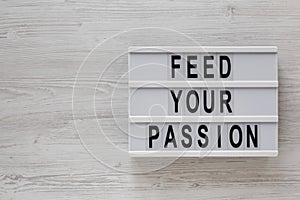 `Feed your passion` words on a modern board on a white wooden background, top view. Overhead, from above, flat lay. Copy space