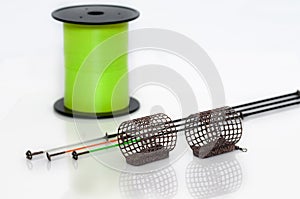 Feeder baskets next to feeder rod tips and green monofilament fishing line spool