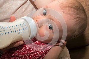 Feeding baby with infant formula in bottle