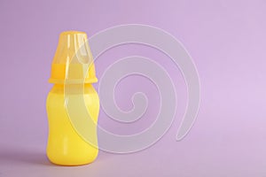 Feeding bottle with infant formula on lilac background, space for text. Baby milk