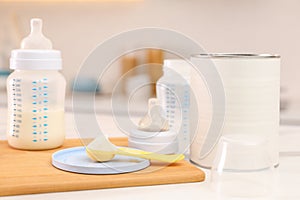 Feeding bottle with infant formula and powder on white table indoors