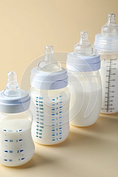 Feeding bottles with baby formula on beige background