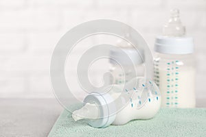 Feeding bottles with baby formula on light grey table. Space for text
