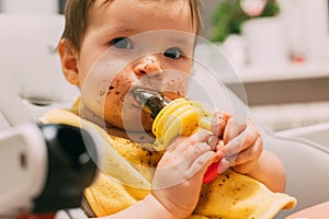 Feeding the child: a cute grimy kid with a dirty face who eats nibbler prunes sitting