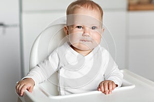 Feeding of cute baby with a spoon in the kitchen