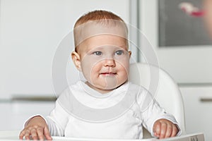 Feeding of cute baby with a spoon in the kitchen