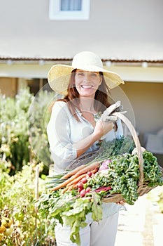 Feeding a family is easy if you put some love into growing veget. A gorgeous woman stands in her garden holding the