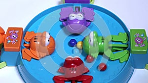 Feeding of four hungry plastic frogs with colored balls. Child game on speed of collecting balls.