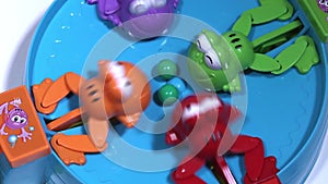 Feeding of four hungry plastic frogs with colored balls. Child game on speed of collecting balls.