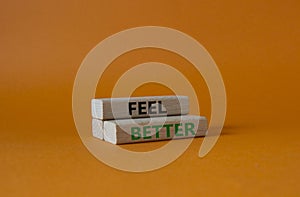 Feel better symbol. Wooden blocks with words Feel better. Beautiful orange background. Business and Feel better concept. Copy