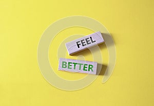 Feel better symbol. Wooden blocks with words Feel better. Beautiful yellow background. Business and Feel better concept. Copy