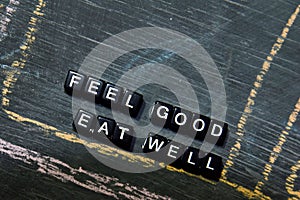 Feel Good Eat Well on wooden blocks. Cross processed image with blackboard background
