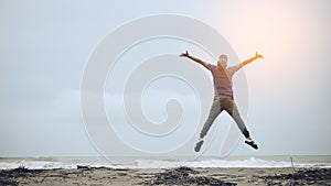 Feel good and freedom concept. Copy space of happy man jumping on beach
