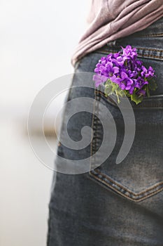 Feel like spring; woman holds a bouquet of colorful flowers in her pants pocket