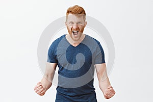 Feel my fury. Portrait of outraged angry and strong masculine redhead male with bristle, clenching fists in anger