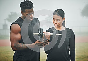 Feel the power flowing from your muscles. a sporty young woman exercising with dumbbells with the help of a trainer