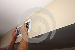 Two Male Hands In Front of a Home Air Conditioning and Heating Vent