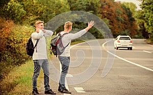 feeling of being free. twins walking along road. stop car with thumb up gesture. hitchhiking and stopping car with