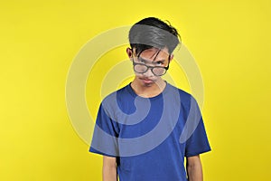 Feeling bored, Young Asian man wearing glasses, isolated on yellow