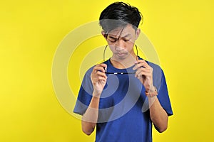 Feeling bored, Young Asian man wearing glasses, isolated on yellow