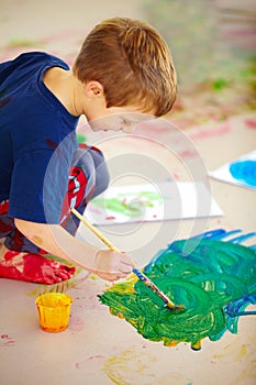 Feeling creative. Cute little boys using fingerpaint on the floor.