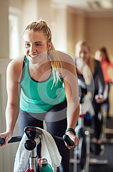 Feeling the effects of an awesome spin class. a young woman working out with an exercise bike in a spinning class at the