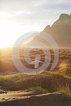 Feeling free. Rear view of young woman, female traveler spreading her arms, enjoying amazing sunrise and wild landscape