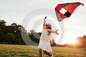 Feeling freedom. Happy girl in white clothes have fun with kite in the field. Beautiful nature