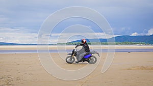 The feeling of freedom and Moto aesthetics. Motorcyclist riding on his bike on sandy beach.