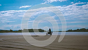 The feeling of freedom and Moto aesthetics. Motorcyclist riding on his bike on sandy beach.