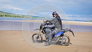 The feeling of freedom and Moto aesthetics. Motorcyclist riding on his bike on sandy beach.