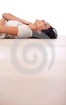 Feeling frisky on the floor. Low-angle view of a beautiful young woman lying on her back on a wooden floor.