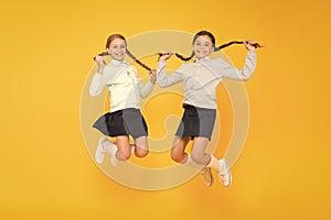 Feeling good fabulous hair. Cute small children with plaited hair jumping on yellow background. Happy little girls