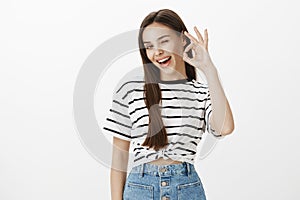 Feeling great, expressing positive mood. Studio shot of carefree confident caucasian female, winking, raising hand and