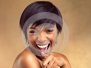 Feeling great and looking even better. Studio portrait of a beautiful young woman laughing against a brown background.