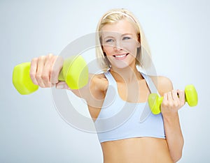 Feeling great. Sporty young woman lifting dumbbells while isolated on white.
