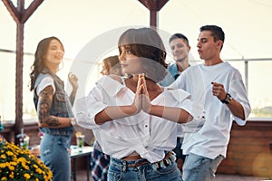 Feeling happy and peaceful. Pretty and young woman in white shirt is holding palms together while enjoying party on