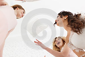 Feeling so happy. View from below of attractive young bride and two bridesmaids making faces while taking selfie in the