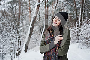 Feeling joy. Cheerful young girl in warm clothes have a walk in the winter forest at daytime